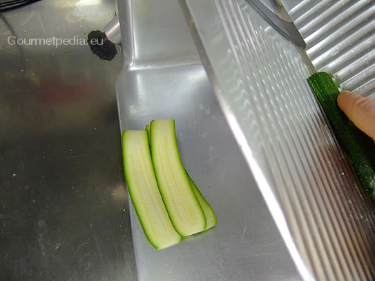 Zucchini waschen, putzen und mit der Aufschnittmaschine in dünne Scheiben schneiden