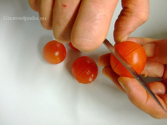 Die gewaschenen Kirschtomaten mit dem Messer auf der glatten Seite kreuzweise einschneiden