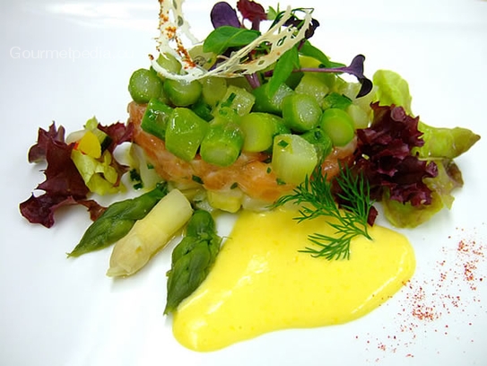 Tartara di salmone con insalata d'asparagi e salsa olandese su insalata estiva