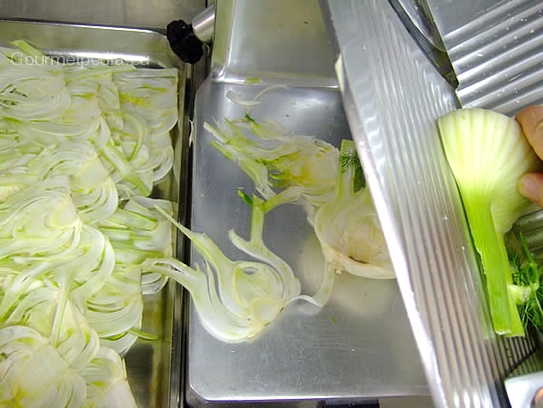 Den geputzten Fenchel mit der Aufschnittmaschiene in hauchdünne Scheiben schneiden