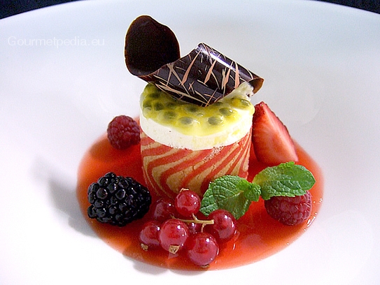 Tartelette au fromage frais à la crème avec la sauce au fruit de la passion, gelée de fraises et fruits des bois