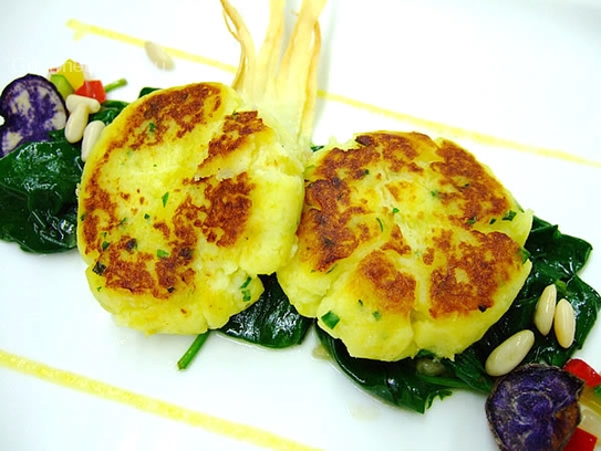 Pastelitos de patata y queso fresco sobre espinacas salteadas con piñones