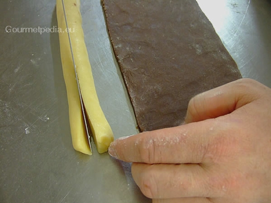 Eine gelbe Teigrolle formen und mit einem scharfen Messer der Länge nach halbieren