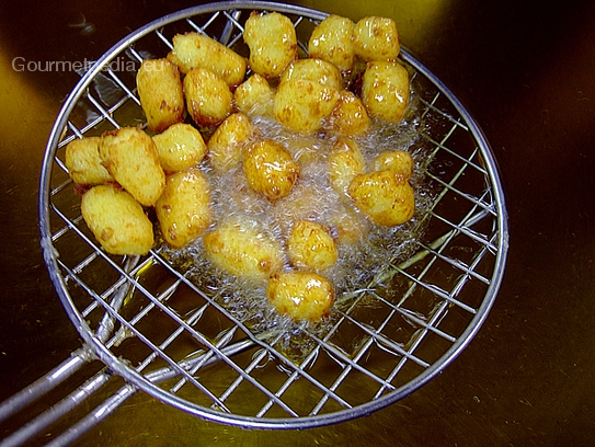 Die goldgelb frittierten Kartoffelnocken aus dem Frittieröl nehmen