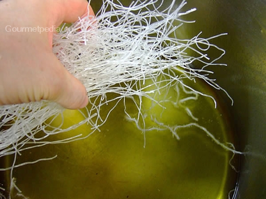 Bei Verwendung von nicht getrockneten Glasnudeln, diese ins heiße Frittieröl einstreuen und mit der Gabel etwas auseinander ziehen