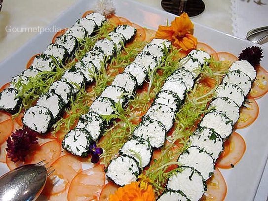 Rollitos de queso fresco de cabra en nido a las hierbas sobre carpaccio de tomates