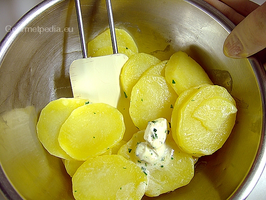 Die blanchierten warmen Kartoffeln eventuell mit Kräuterbutter vermischen