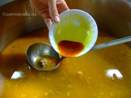 Aufgelöstes Safranpulver in die Fischsuppe einrühren und diese dann kräftig abschmecken