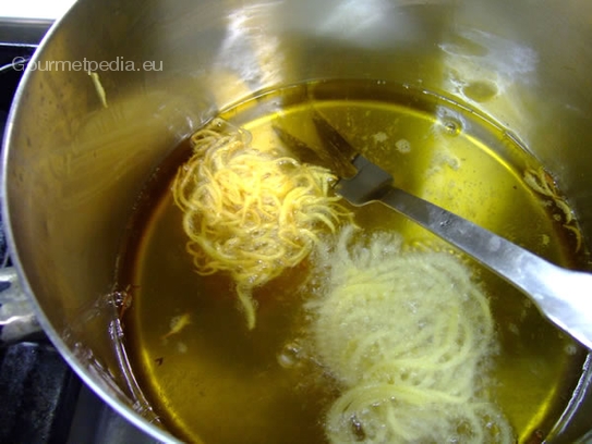 Die Kartoffelspaghetti in heißen Öl knusprig frittieren