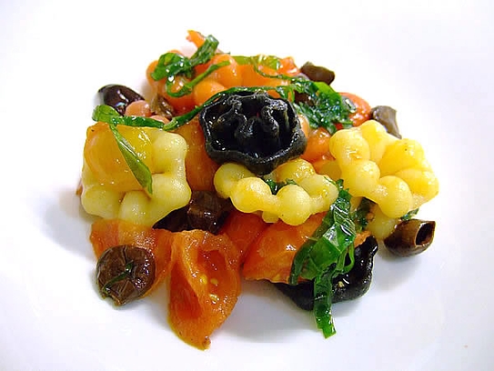 Coloured pasta with olives, small mozzarelline, cherry tomatoes and basil