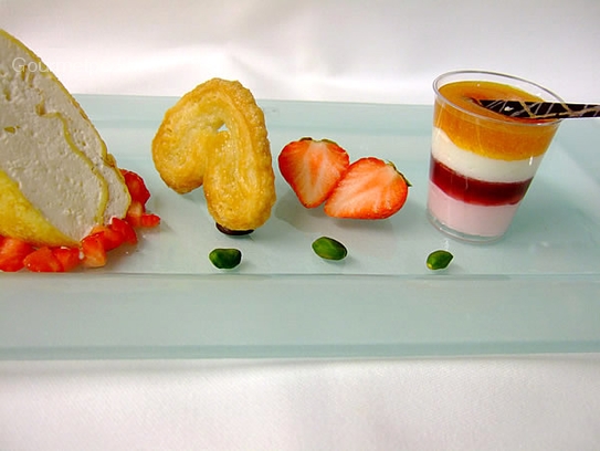 Yogurt roulade in crêpes on marinated strawberries and raspberry mousse with apricot jelly