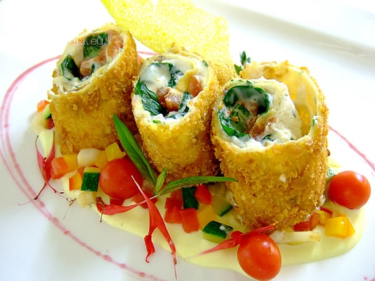 Rollitos de crepe rellenos de queso y tomate sobre verduras salteados