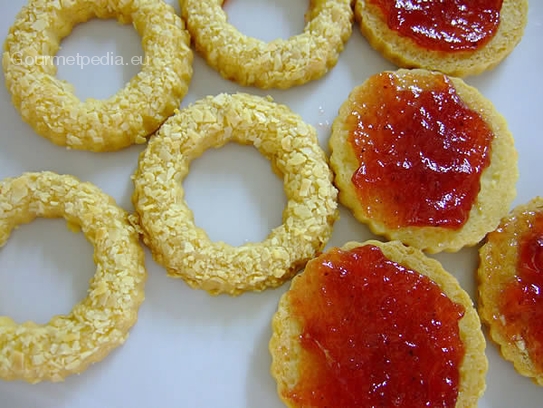 Die Böden für die Mandel-Spitzbuben mit Erdbeermarmelade bestreichen und die Mandelringe aufsetzen