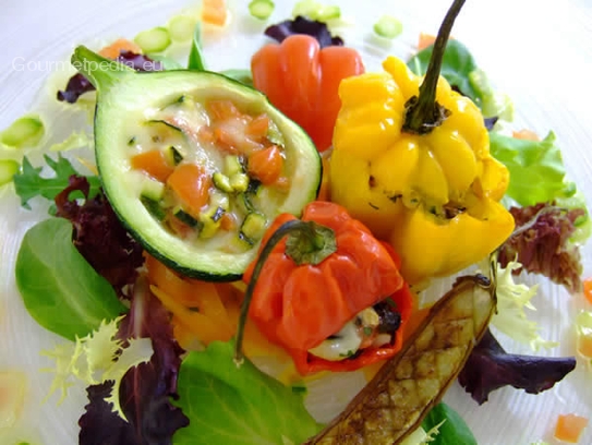 Die gegarten Mini-Paprika und Zucchinis mit gegrillten Mini-Auberginen auf marinierten Salaten anrichten