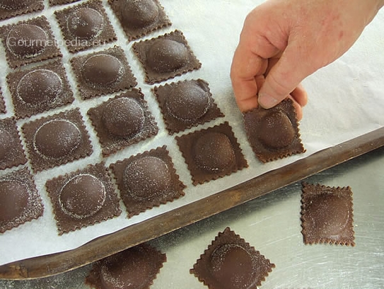 Bis zum Kochen die Ravioli auf ein mit Hartweizenmehl bestreutes Backpapier legen und mit einem Tuch abdecken