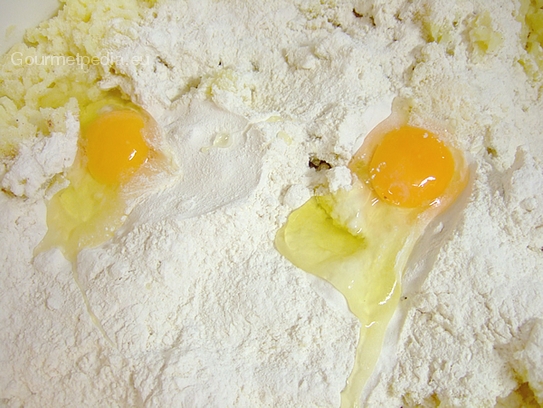 Zutaten wie Muskatnuss, Butter Salz, Pfeffer und Eier auf die passierten Kartoffeln geben