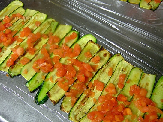 Die Tomatenwürfel auf den Zucchinischeiben verteilen