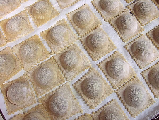 Bis zum Kochen die Ravioli auf ein mit Hartweizenmehl bemehltes Backpapier legen und mit einem Tuch abdecken