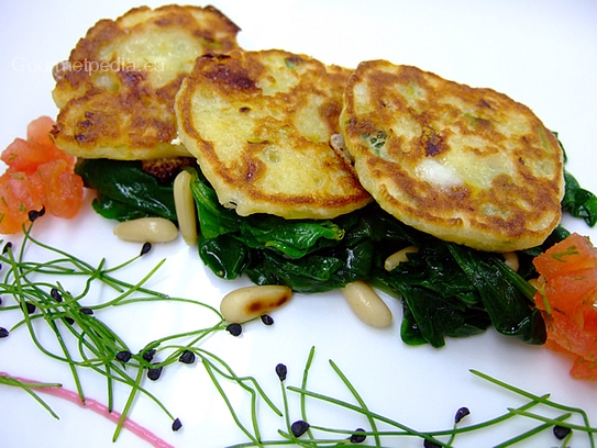 Blinis de queso sobre espinacas salteadas con piñones tostados