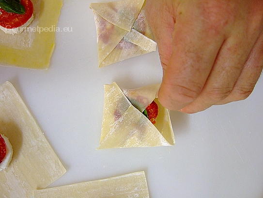 Für die Wonton zum Braten die Ränder vom Teigblatt mit verquirlten Ei bestreichen und die Ecken zur Mitte zusammen falten