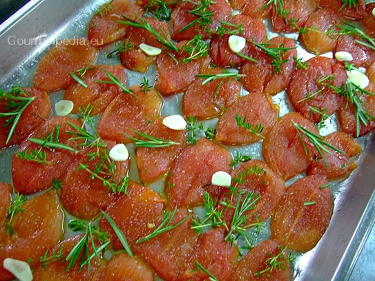 Zubereitung von mehreren Tomatenfilets mit ganzen Knoblauch und Kräutern nach Wahl