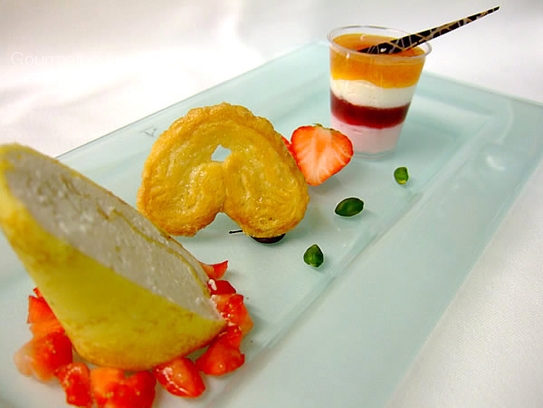 Yogurt roulade in crêpes on marinated strawberries and raspberry mousse with apricot jelly