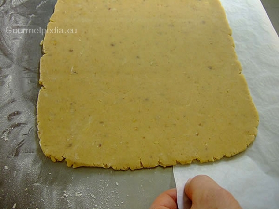 Das Backpapier unter die Teigplatte durchziehen oder auf das Rollholz aufrollen