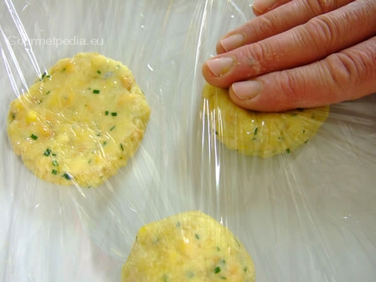 Die Knödel zwischen zwei Lagen Klarsichtfolie  auf 1cm flach rund drücken und im Kühlhaus abgedeckt mit Klarsichtfolie bis zum Kochen lagern