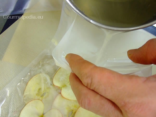 Den heißen Zuckersirup in den Vakumierbeutel auf die Apfelscheiben gießen