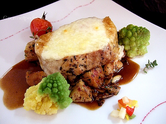 Steak di sella di vitello gratinato con formaggio su rosticciata di porcini e canederli, romanesco sauté