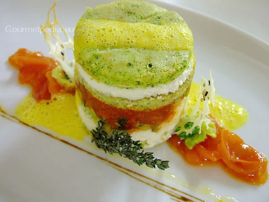 Serviervorschlag von Kräuterflan mit Zucchini und Tomaten mit Safranschaum auf sautierten Kirschtomaten