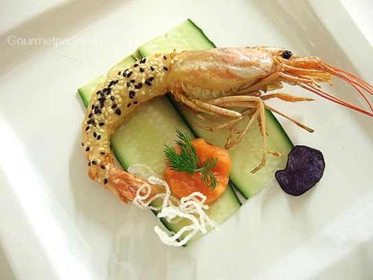 King prawn in tempura batter for deep frying with sesame on a beet of cucumbers with avocado tartare