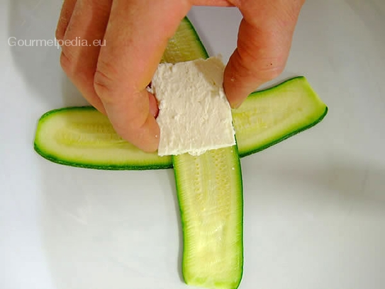 Feta-Käse in flache Würfel schneiden und auf die Zucchini legen