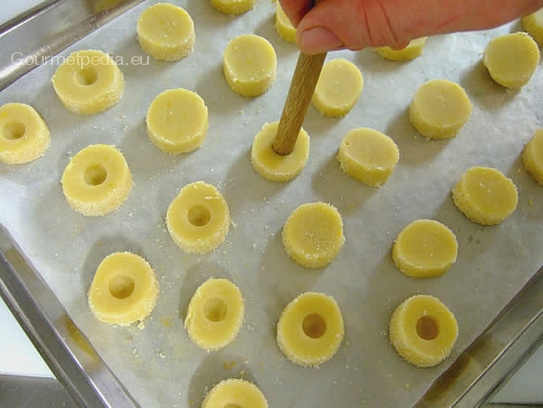 Die Teigscheiben mit etwas Abstand auf ein Backblech mit Backpapier legen und mit einem Kochlöffelstiel kleine Mulden mittig eindrücken