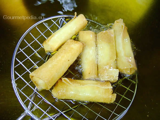 Die knusprig frittierten Ananasröllchen aus dem Frittieröl nehmen