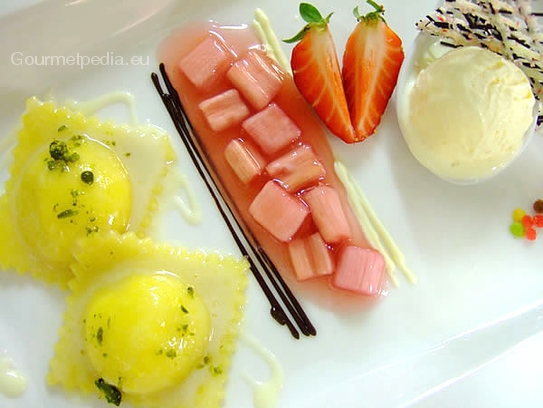 Serviervorschlag von den Vanilleteigtaschen mit weißer Schokoladensauce an Rhabarberragout