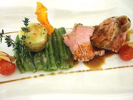 Roast saddle of veal with aromatic herb sauce on a beet of green beans and baked potato