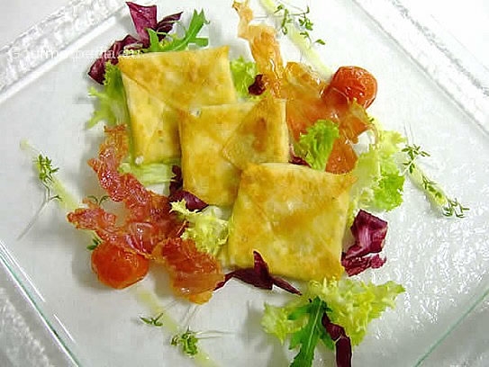 Raviolis "wonton" salteados, rellenos de queso fresco de cabra sobre ensalada marinada con tocino crujiente