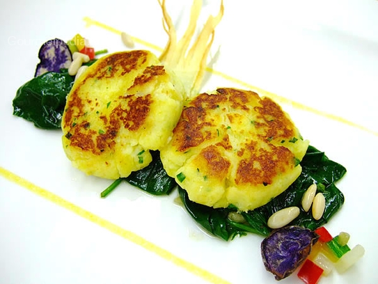 Pastelitos de patata y queso fresco sobre espinacas salteadas con piñones