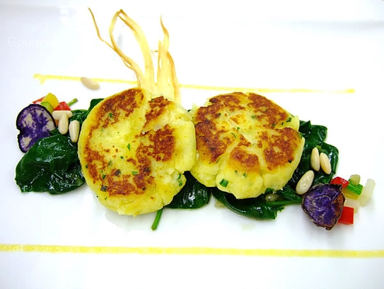 Pastelitos de patata y queso fresco sobre espinacas salteadas con piñones