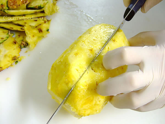 Die Ananas mit dem Messer halbieren