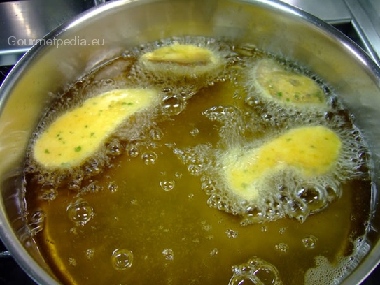 Die panierten Steinpilze in dem heißen Fett frittieren